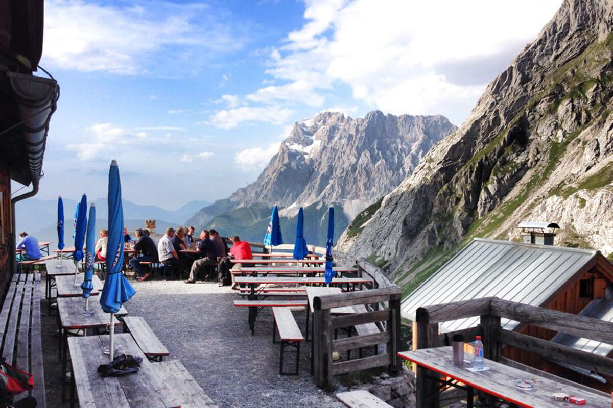 Die Coburger Hütte – mit Blick auf die Zugspitze. Von der Terrasse hat man einen schönen Blick hununter ins Tal, auf die Zugspitze und über den Seeben- und den Drachensee.