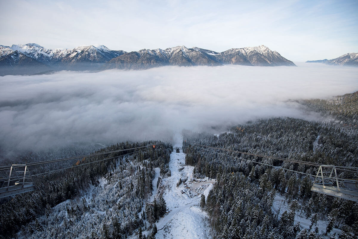 Seilbahn Zugspitze – Drahtseilakt. GANZ SCHÖN LUFTIG: Der Blick von der neuen Seilbahnstütze auf die Ammergauer Alpen. Unten liegt die bereits abgebaute Stütze der alten Bahn im frischen Neuschnee