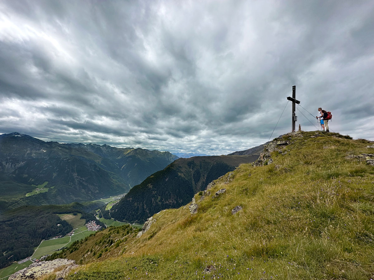 Grasgipfel unter Grauwolken: Blick von der Mahdebene auf den Ortsteil Tölderboden in Niederthai.