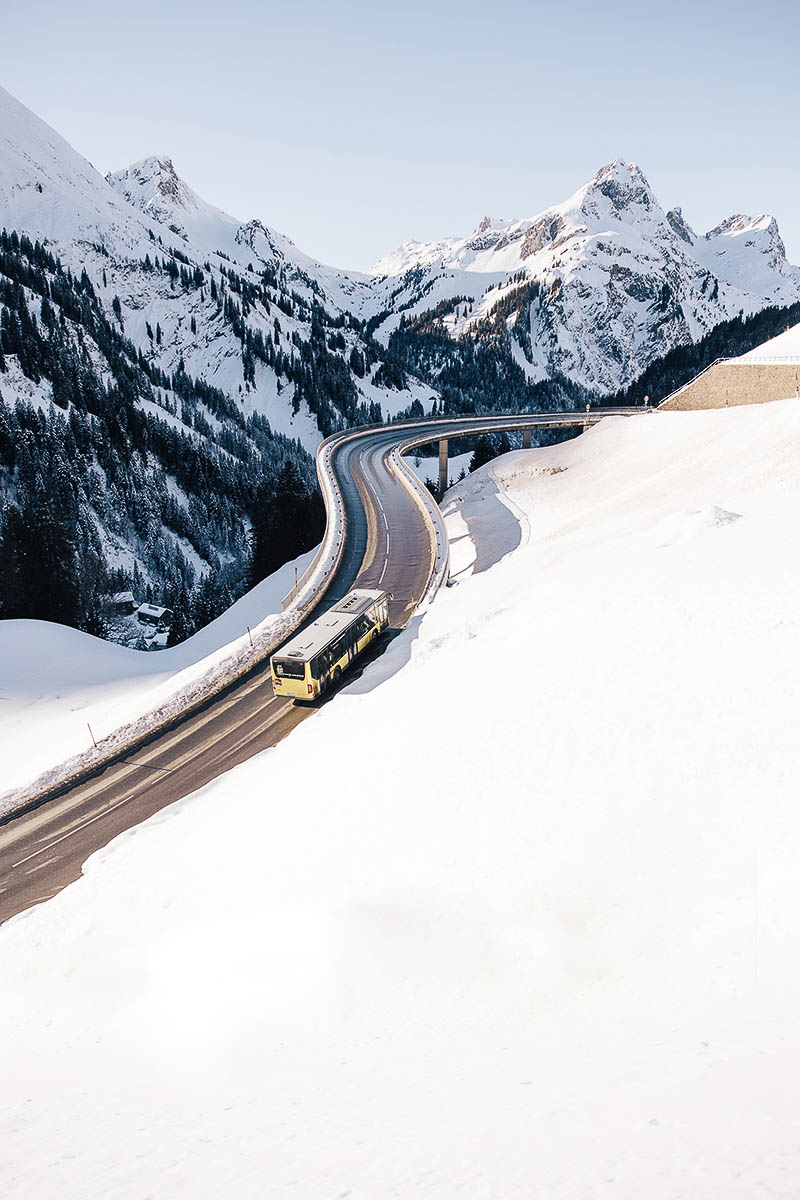 Skibus fährt über die verschneite Passstraße zwischen Warth und Schröcken im Arlberggebiet
