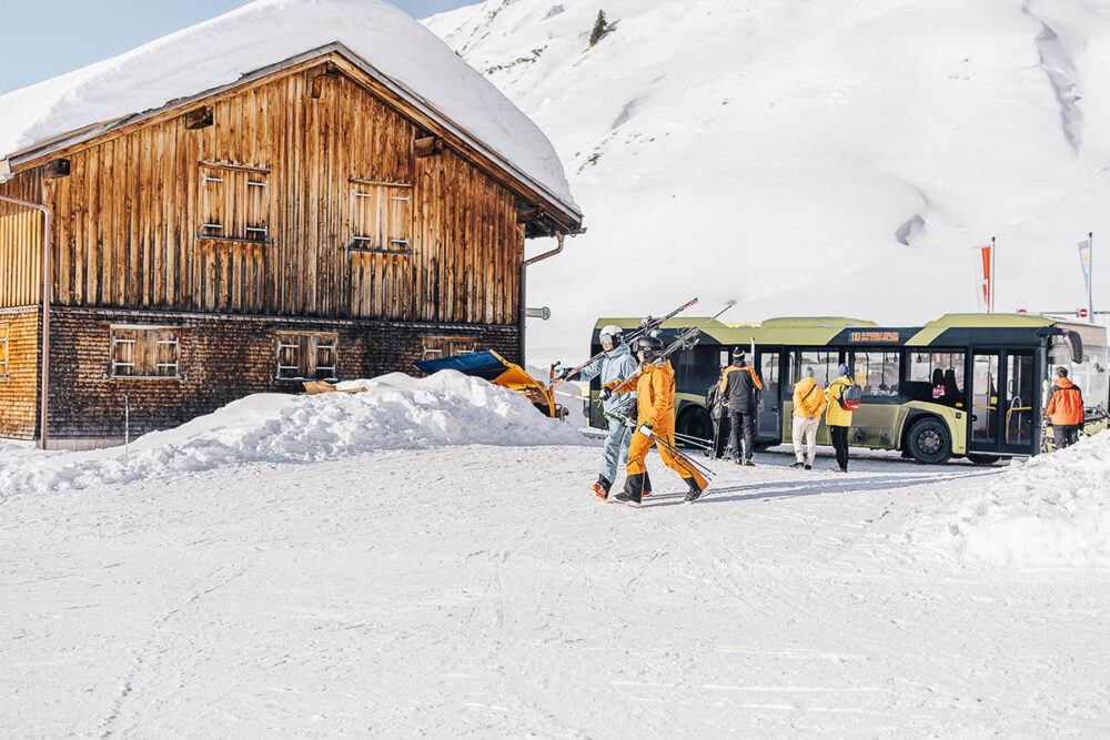Skifahrer steigen in Warth-Schröcken aus dem Skibus im tief verschneiten Arlberggebiet aus