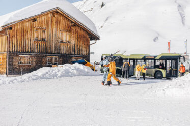 Skifahrer steigen in Warth-Schröcken aus dem Skibus im tief verschneiten Arlberggebiet aus
