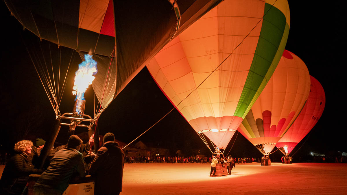 Aus dem Dunkeln ins Licht: Beim Winter-Ballonfestival im Tannheimer Tal steigen die Ballone frühmorgens in die klare Alpenluft.