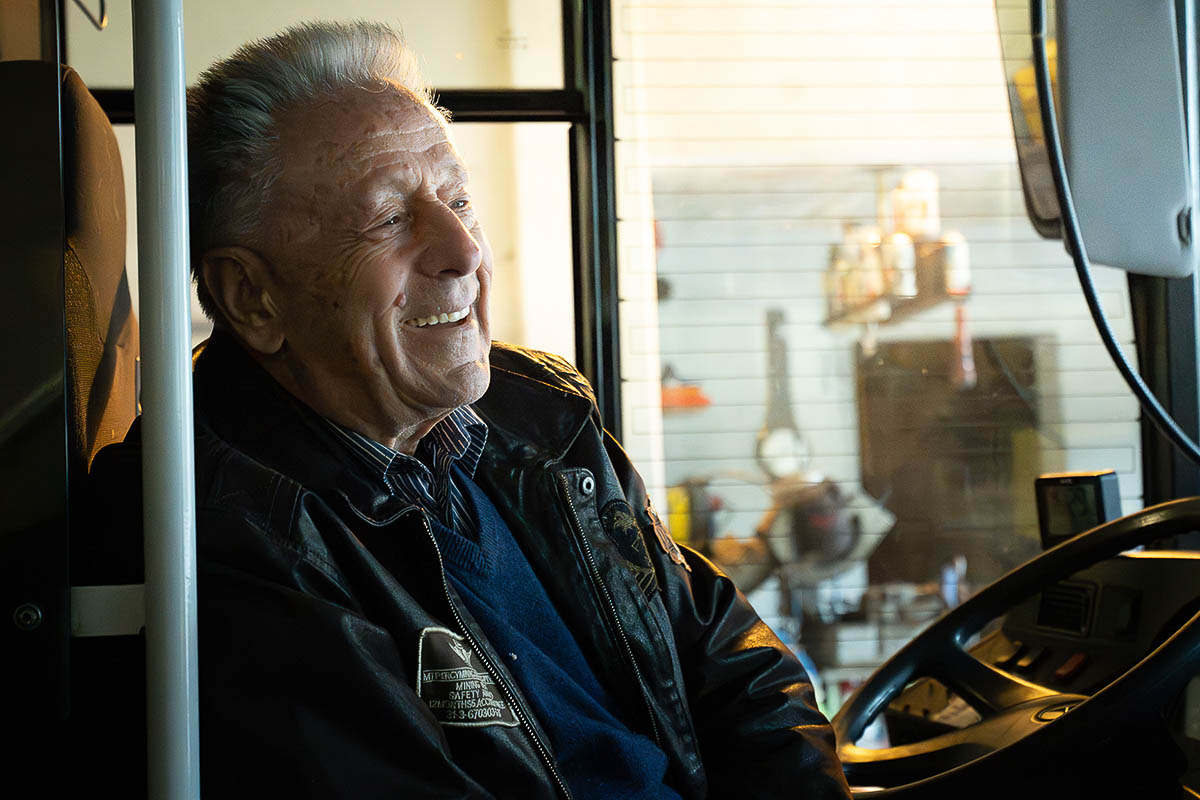 Skibusfahrer sitzt lächelnd am Steuer eines Linienbusses im Skigebiet Warth-Schröcken