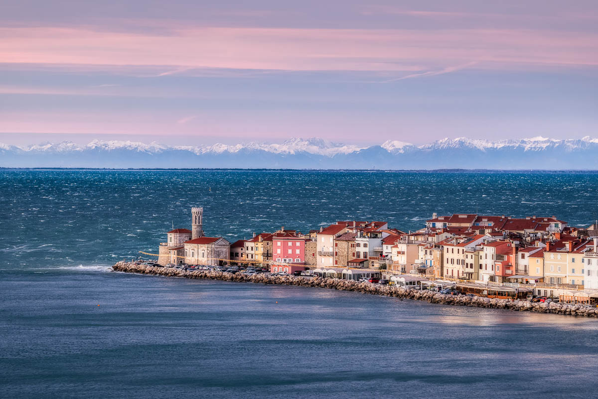 Blick auf die Altstadt von Piran an der Punta, dahinter die schneebedeckten Alpen und das winterliche Adriatische Meer. Copyright: Jaka Ivančič