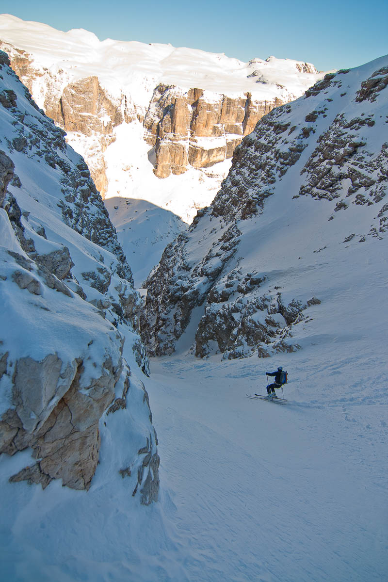 Skialpinist in einer engen Couloir-Rinne in den Dolomiten – Steilwandskifahren zwischen hohen Felswänden.