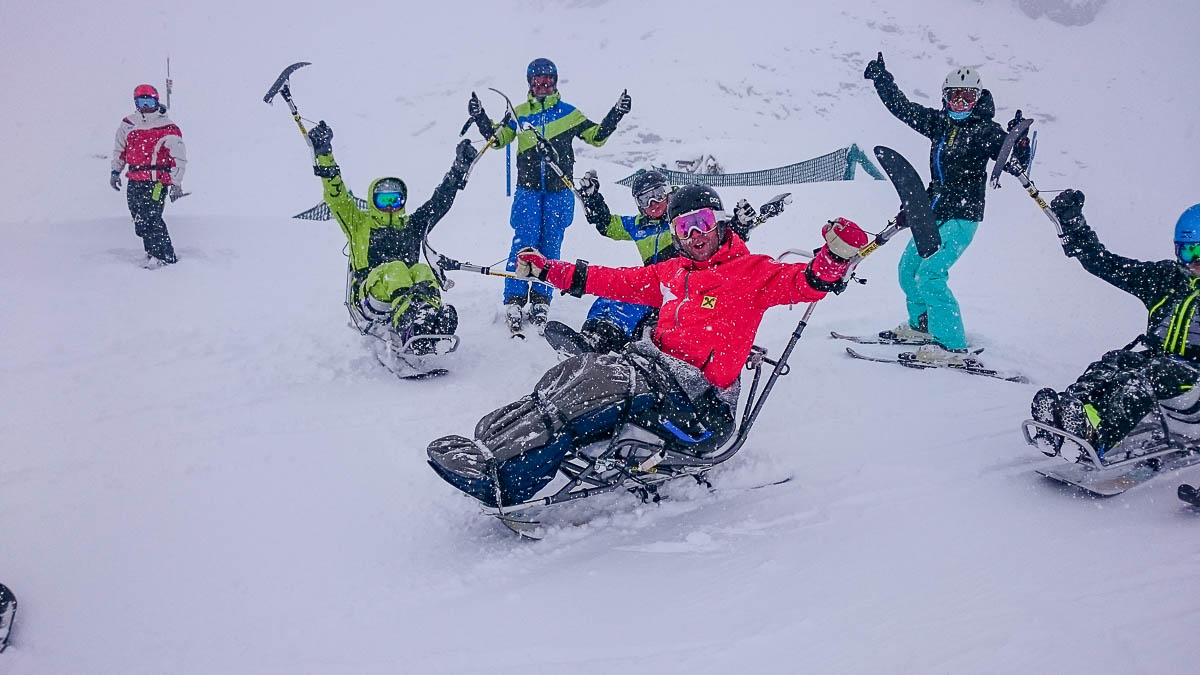 Gruppe von Wintersportlern mit Behinderung im Bi-Ski während eines inklusiven Skikurses in Tirol.