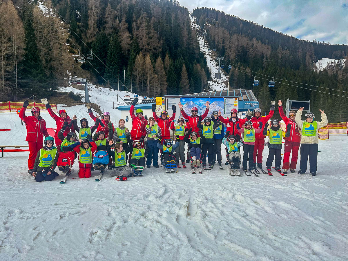 Gruppe von Kindern mit Behinderung und Skilehrern der Skischule Snowpower beim inklusiven Skikurs in Tirol.