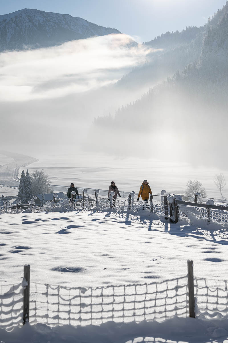 Winterwanderer bei Oberammergau mit Blick auf verschneite Wiesen und die Ammergauer Alpen.