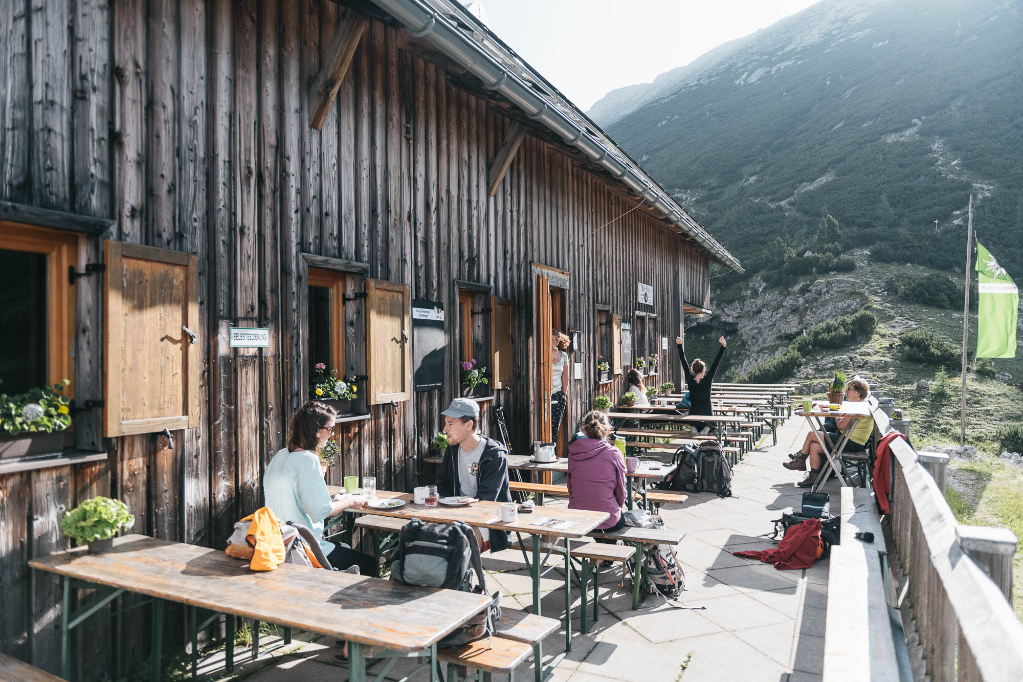 Gäste auf der Sonnenterrasse der Hesshütte im Gesäuse