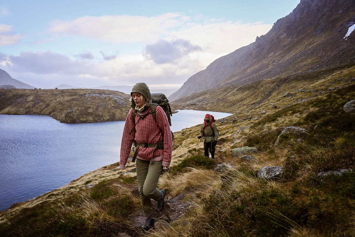 Zwei Wanderer tragen Wollpullover in alpiner Landschaft beim Wandern