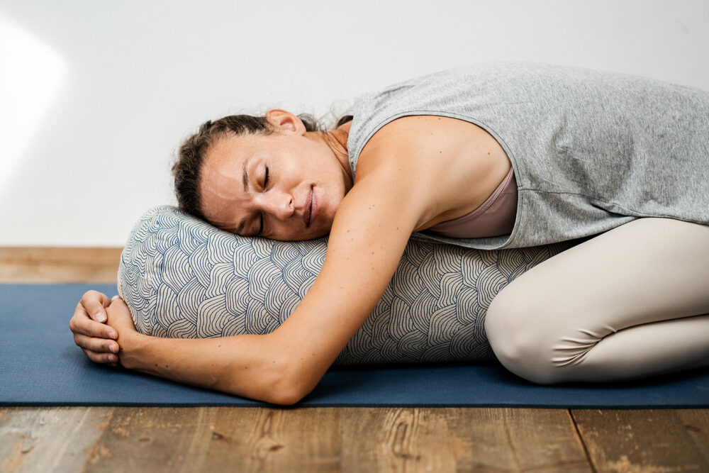 Frau entspannt auf Yoga-Kissen aus Bio-Dinkelspelz während Yoga-Session