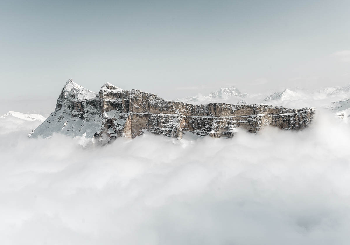 Luftaufnahme verschneiter Dolomiten mit Nebel und schroffen Felsstrukturen