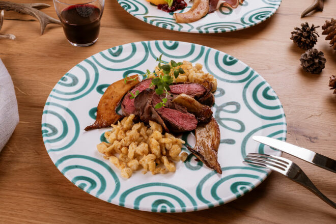 Rosa gebratener Rehrücken mit Spätzle, Kräuterseitlingen und Preiselbeeren auf Teller angerichtet