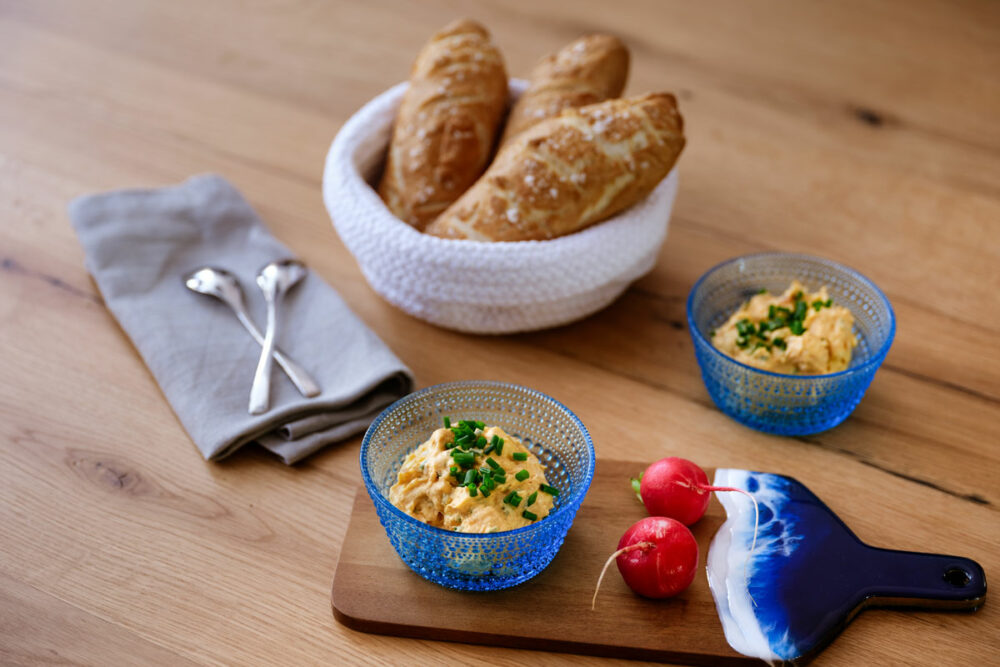 Klassischer bayerischer Obazda mit Schnittlauch und Brezn auf rustikalem Holztisch serviert