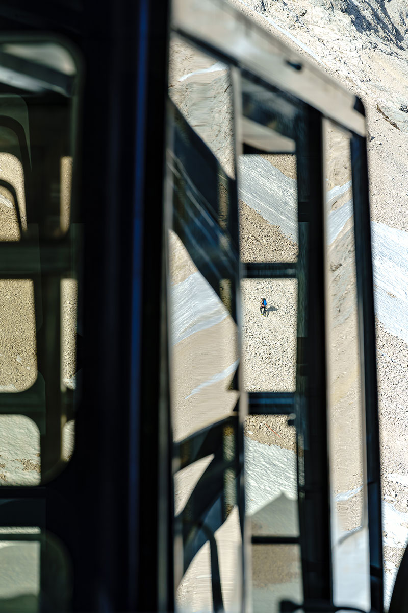 Ein Bergsteiger steigt über das felsige Gelände zur Zugspitze auf, fotografiert aus der vorbeifahrenden Zugspitzbahn.