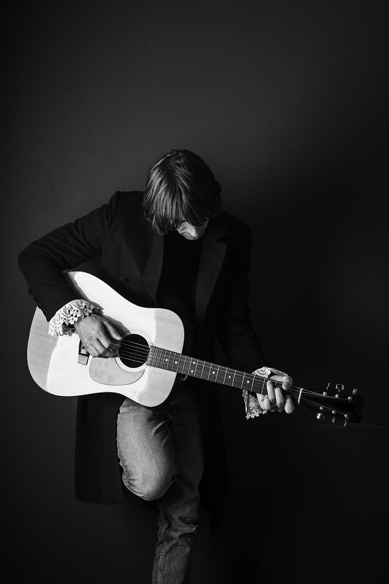 Max von Milland spielt Gitarre bei einem Schwarz-Weiß-Fotoshooting