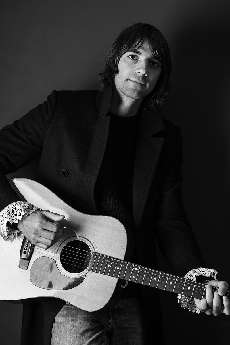 Musiker Max von Milland mit Gitarre im Schwarz-Weiß-Porträt