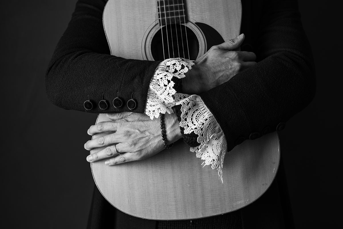 Detailaufnahme von Max von Milland mit Gitarre und Spitzenärmeln der Brixner Tracht