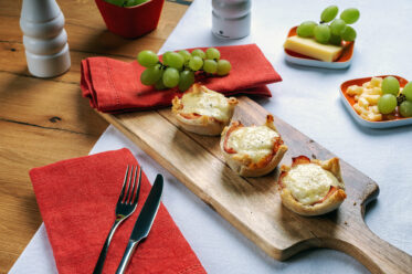 Croque-Madame-Muffins mit Schinken, Ei, Béchamel und Comté auf einem Holzbrett.