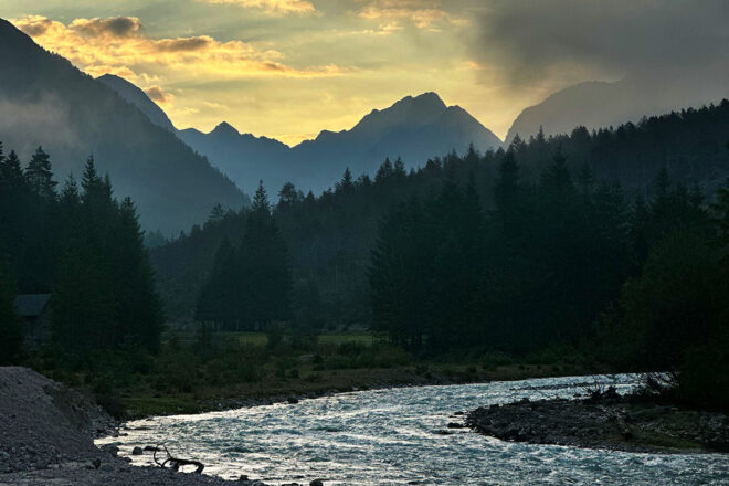 Die Isar im Hinterautal bei Scharnitz im Morgengrauen, dahinter die Silhouetten der Karwendelberge.