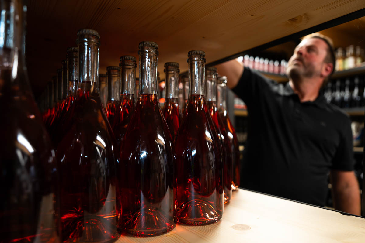 Roséweinflaschen im Vordergrund und Peter Somweber im Weinlager des Trueferhofs